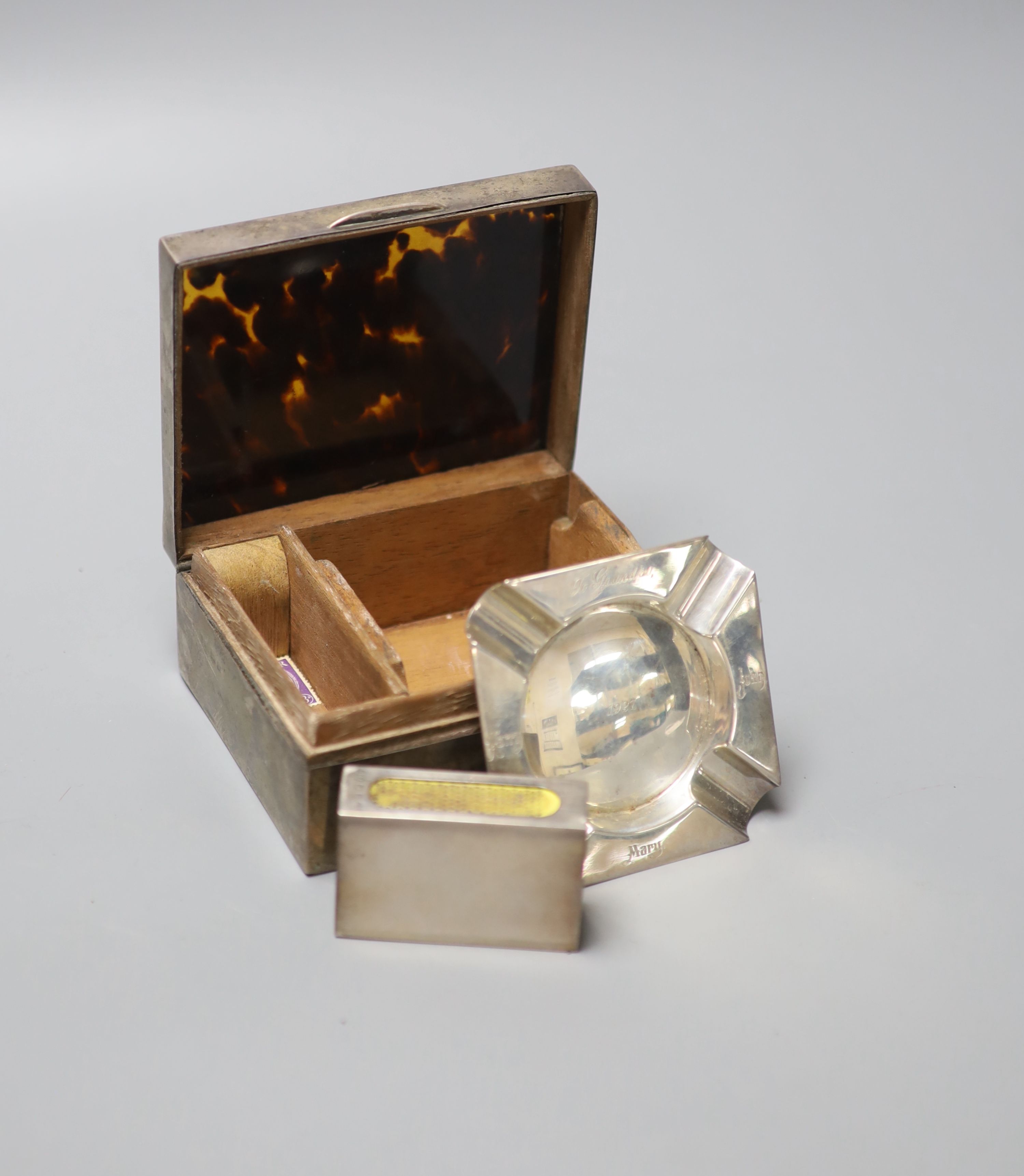 A 1920s silver and tortoiseshell mounted cigarette box, containing a fitted matched silver ashtray and mounted matchbox sleeve,